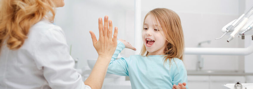 Dentista chocando la mano a niña en consulta