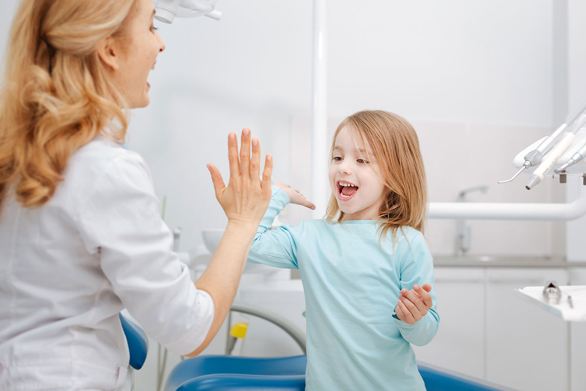 Dentista chocando la mano a niña en consulta